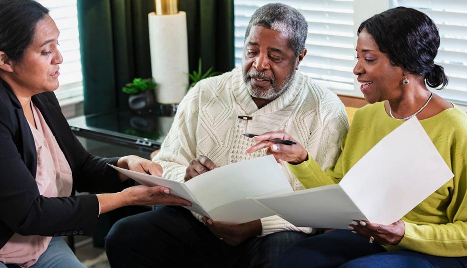A senior African-American couple meeting with a consultant. They are sitting in the living room signing paperwork.
