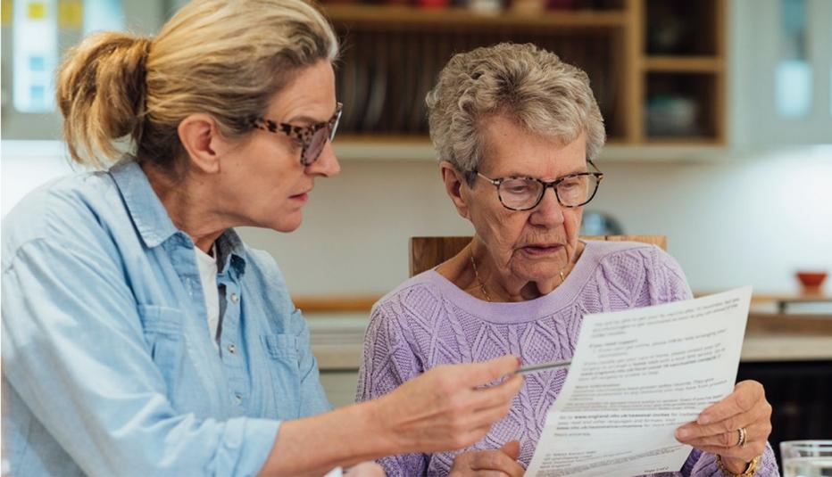 A daughter looks at important paperwork with her elderly mother.