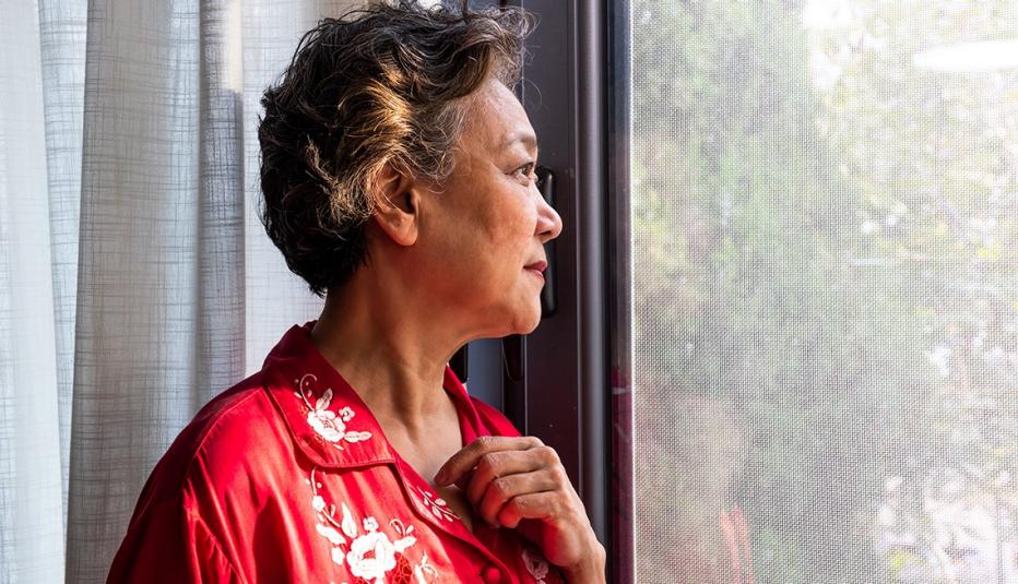 An elderly woman looks out the window
