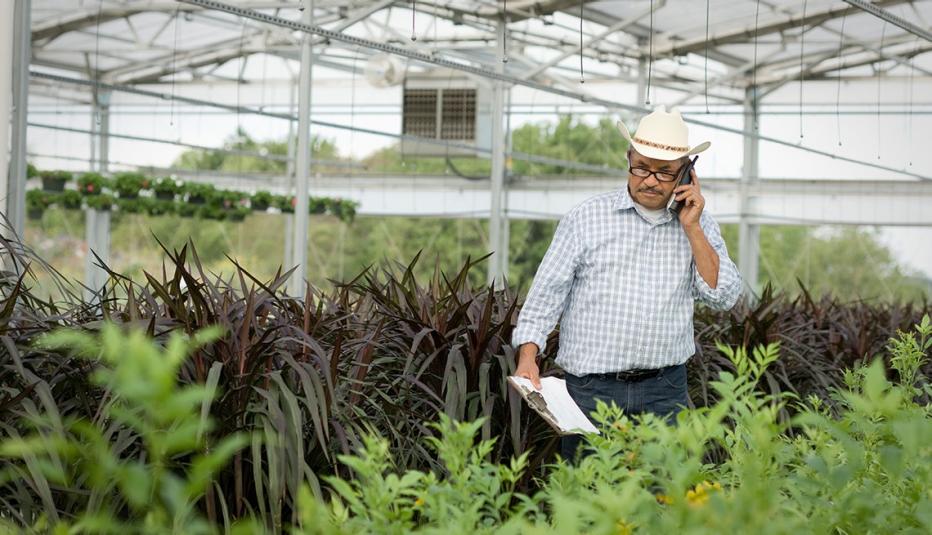 Hispanic man talking on cell phone in greenhouse