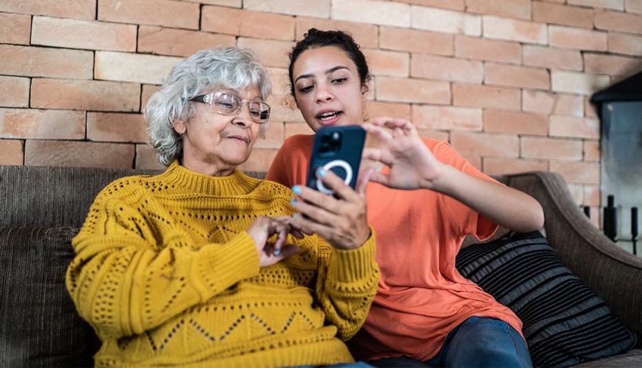 Granddaughter helping grandmother to use the mobile phone at home