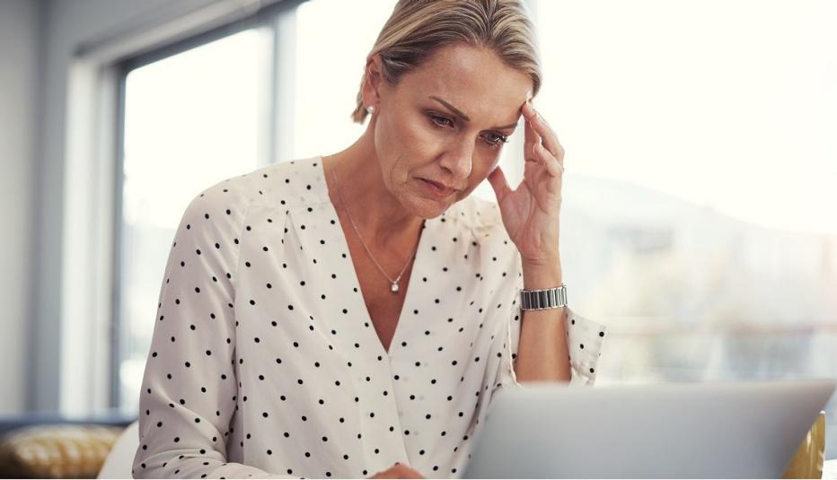 woman looking at laptop screen with troubled expression