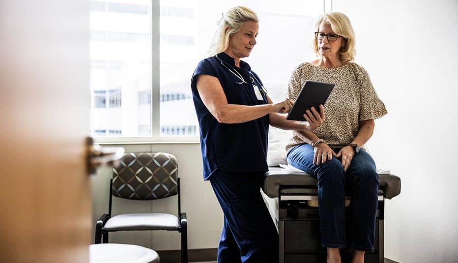 Female doctor in scrubs consulting with senior woman in exam room