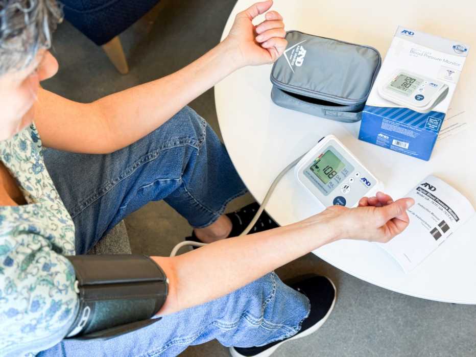 Woman sits and takes a blood pressure reading using the A&D Medical Premium Multi-User monitor