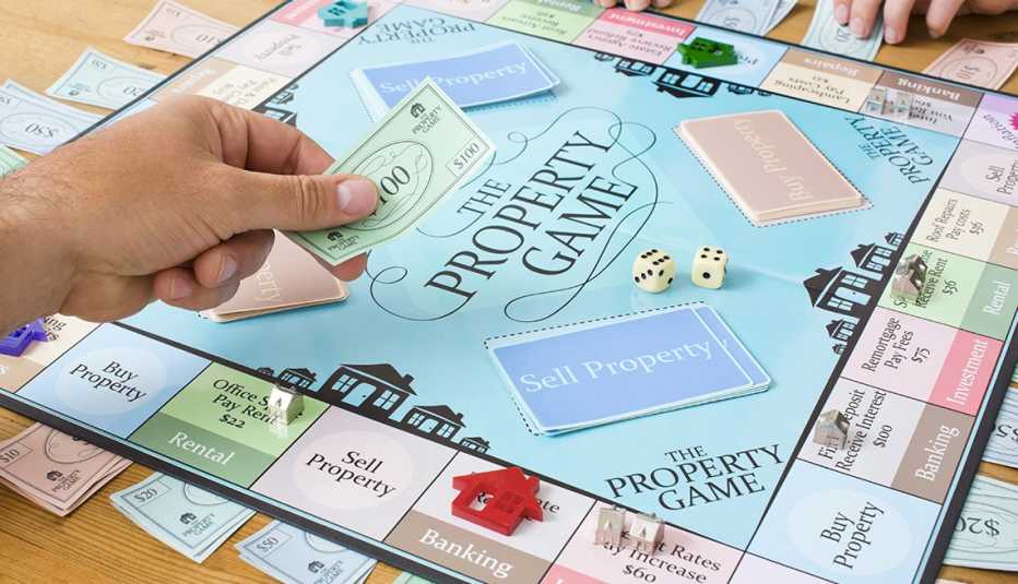 adult hands play money to a child  while playing a board game about property