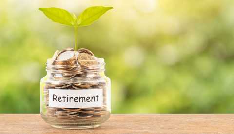 jar full of coins marked retirement with a young plant sprouting out of it