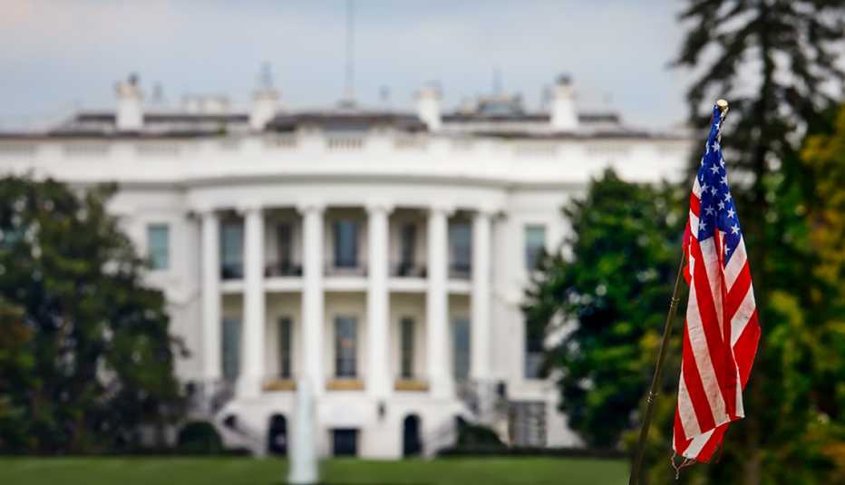 The American flag with the White House behind it