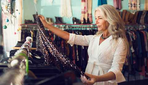 A woman holds and looks at a dress inside a clothing store