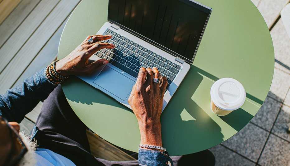 overhead view of a man working on a laptop outdoors at a small table