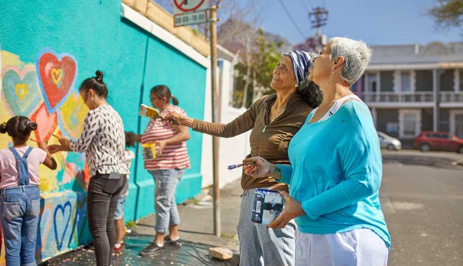 a group of four women and two children painting the outside of a building