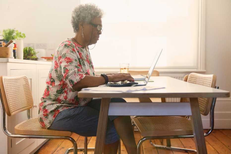 Older woman sitting at a table using a laptop