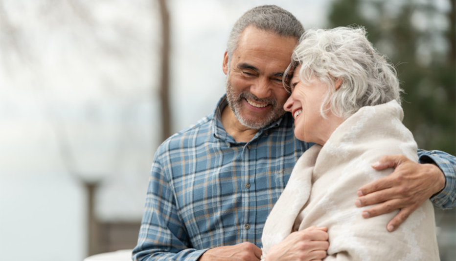 man hugging a woman wearing a blanket around her shoulders