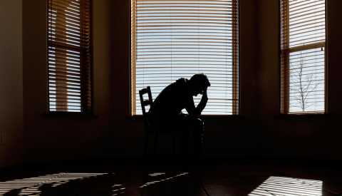 silhouette of a man sitting in a chair with his head in his hands