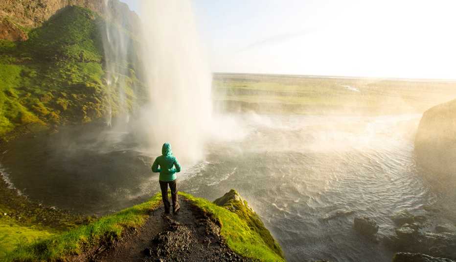 a woman hiking near seljalandsfoss waterfall in iceland