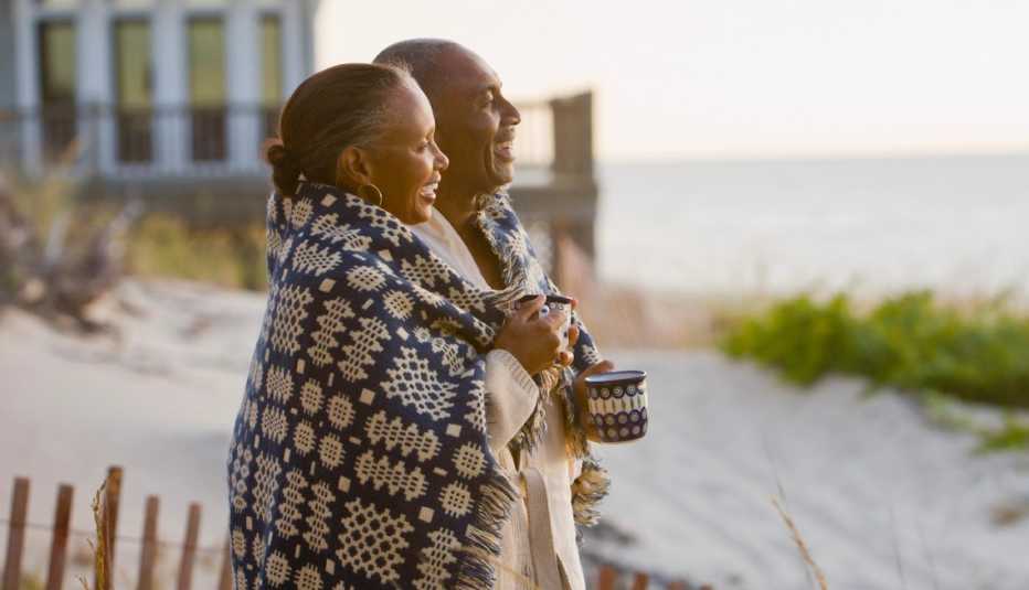romantic couple wrapped in a blanket on the beach at sunset