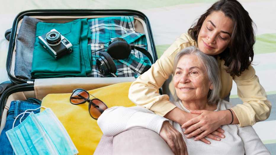 A woman embraces her mother next to an open suitcase