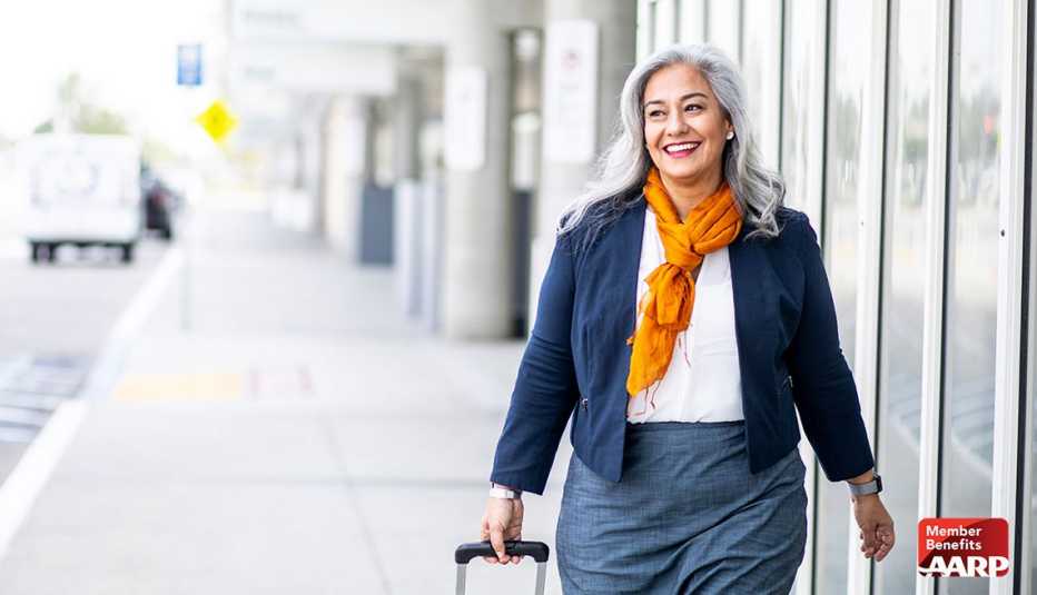 lady with gray long hair strolling outside airport with luggage