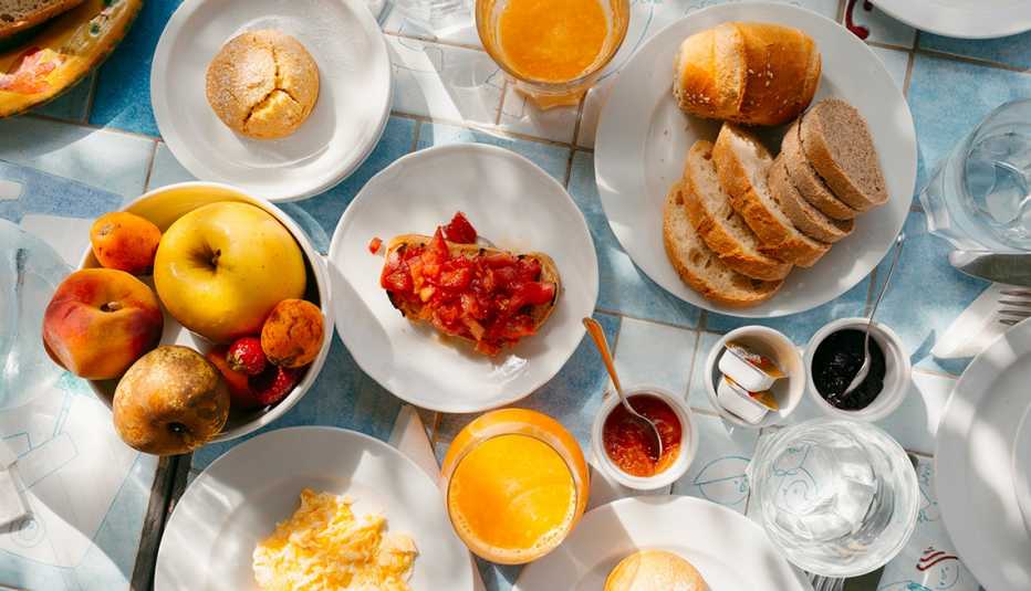 plates and bowls with all sorts of food, including fruit, bread, bruschetta, a muffin; glass of orange juice, glass of water