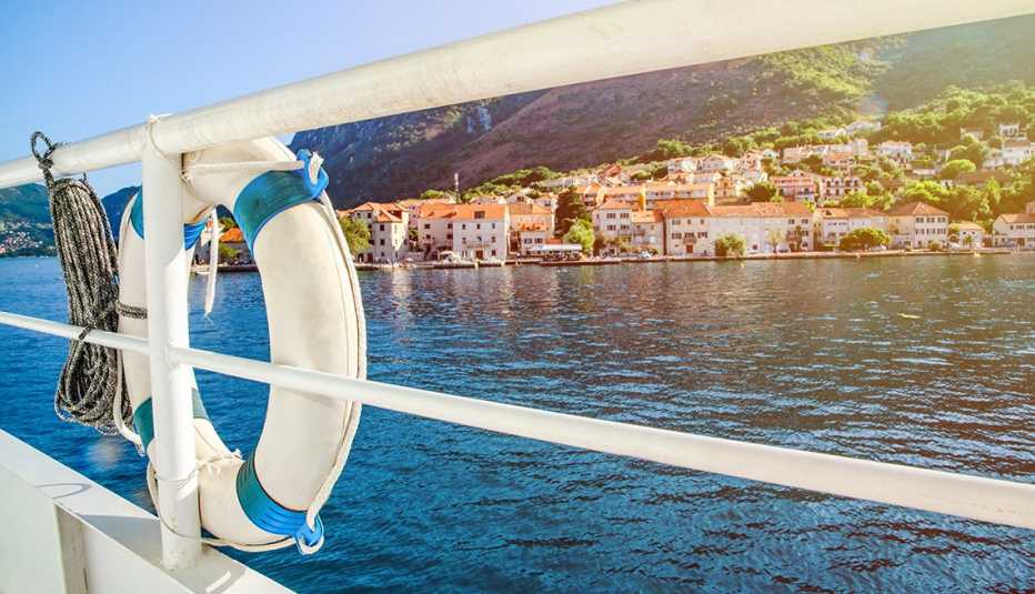 view from boat, looking through rails at water; buildings in the distance