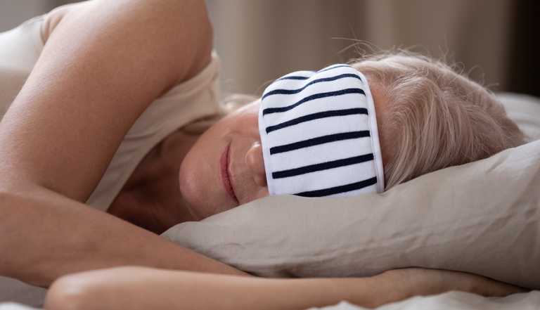 woman wearing a sleep mask while sleeping at a hotel