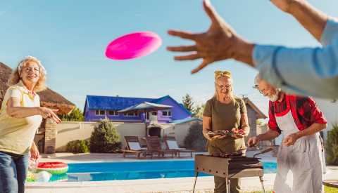 Group of cheerful active senior people having a backyard barbecue party