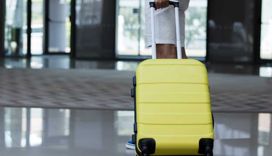 Man with yellow suitcase waiting in a hotel hallway