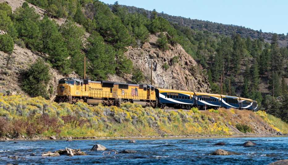 rocky mountaineer train driving past a mountain and a river