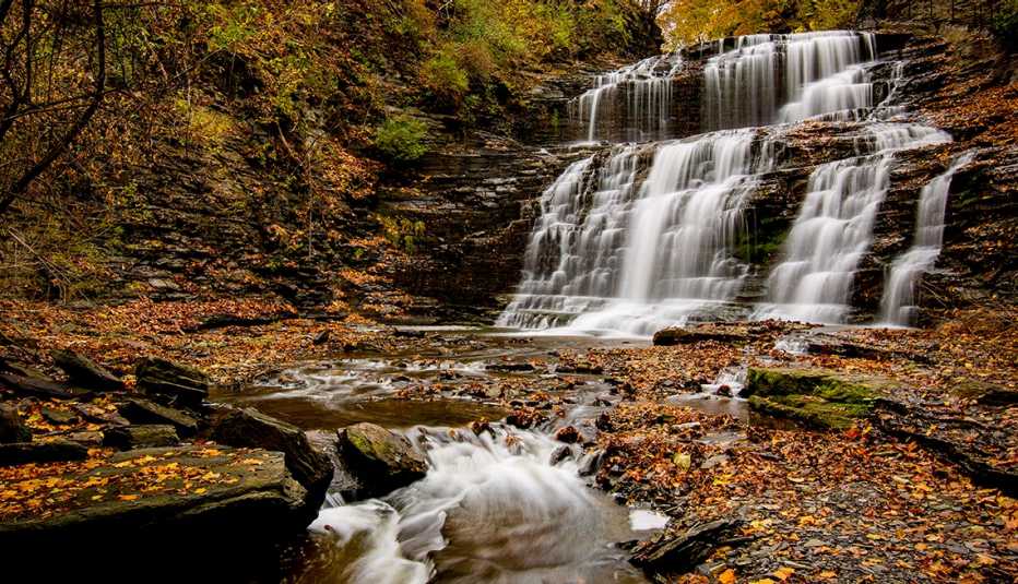 waterfall at cascadilla gorge cascades down to a rocky ground covered with leaves waterfall at cascadilla gorge cascades down to a rocky ground covered with leaves