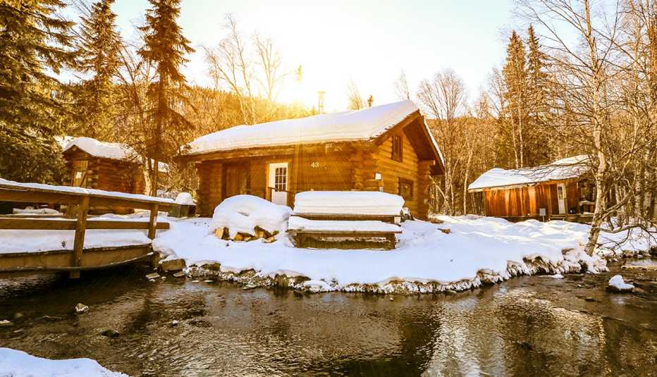 a cozy cabin surrounded by a snowy forest and a stream