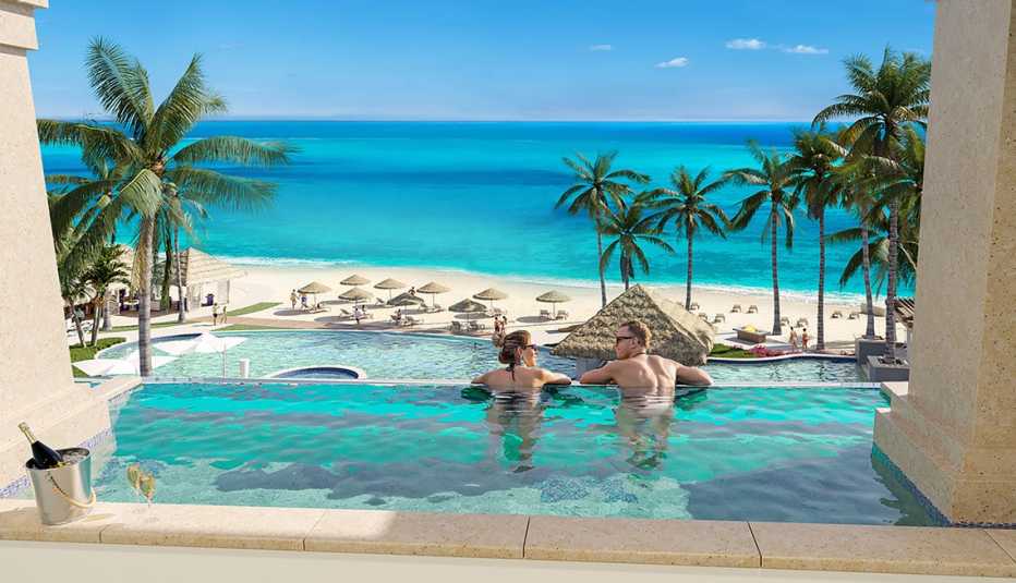 two adults lounge in a pool overlooking the carribean ocean in sandals dunns river adults only resort