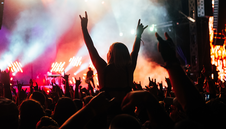 a girl in the crowd throwing horns at the twenty twenty two louder than life music festival in louisville kentucky