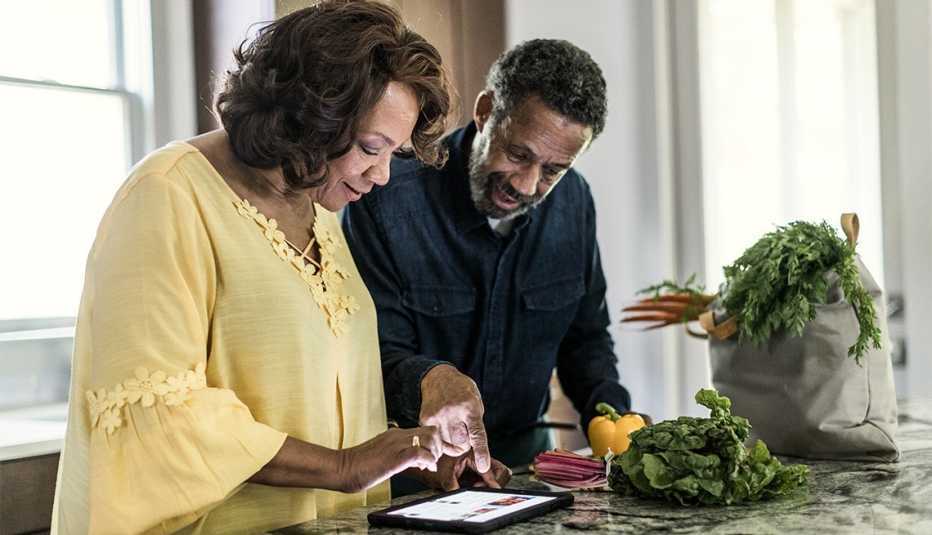 couple using tablet in kitchen to cook a meal