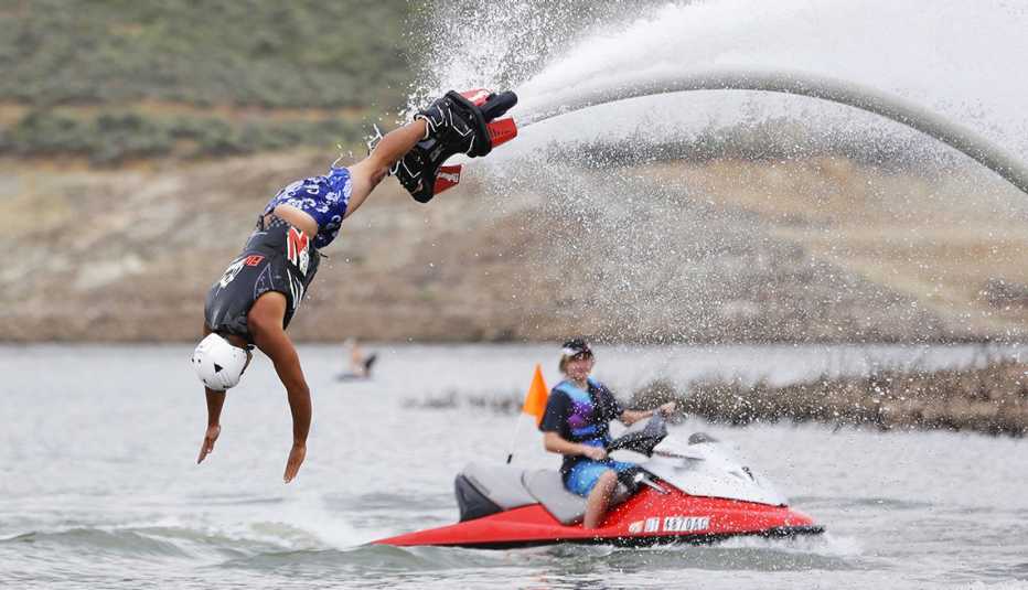 one person on jet ski, while other is diving into water
