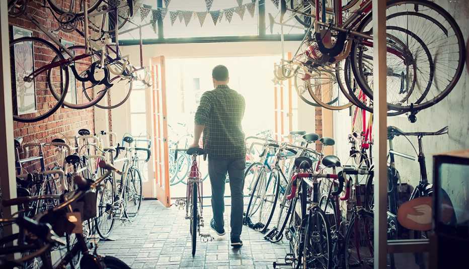 Man walking out of a bicycle shop with a new bike.