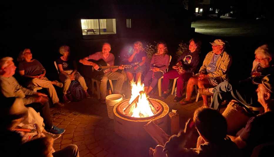 gathering of adults around a campfire singing and playing instruments