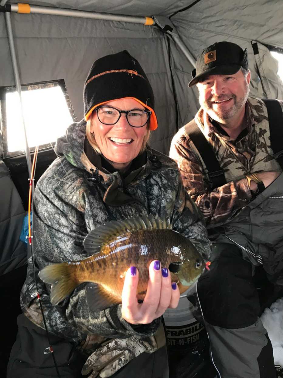 a man and woman ice fishing holding a caught fish