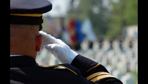 Army soldier renders salute at cemetery