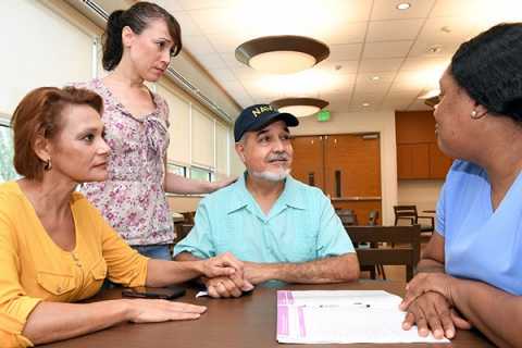 A veteran family sitting at a table discussing patient file with a healthcare worker