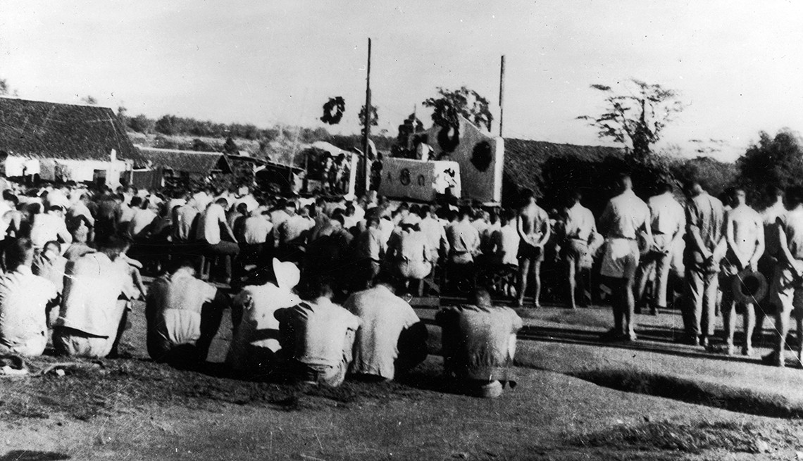 American and Filipino prisoners celebrating Christmas in the Cabanatuan POW camp on December 25, 1943. Prisoners gather on the grounds of the Cabanatuan POW camp