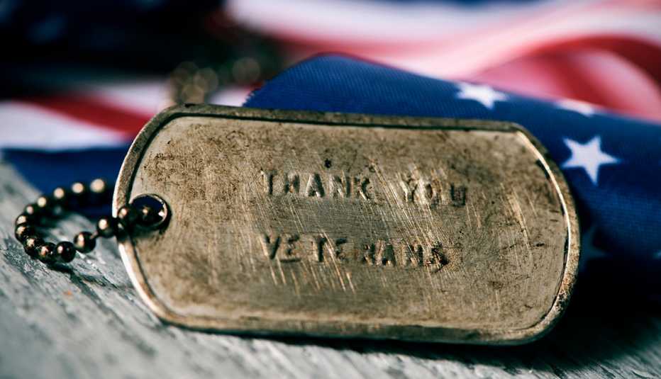 869290754 closeup of a rusty dog tag with the text thank you veterans engraved in it, next to a flag of the United States