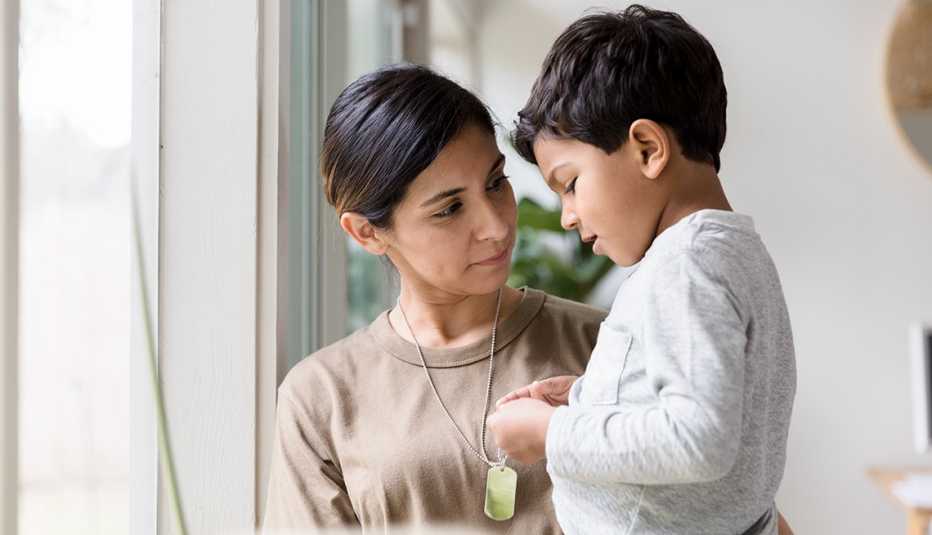 A woman is standing by a window holding a child A woman is standing by a window holding a child