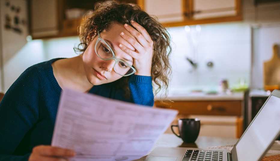 A woman sitting at a table looking at a bill