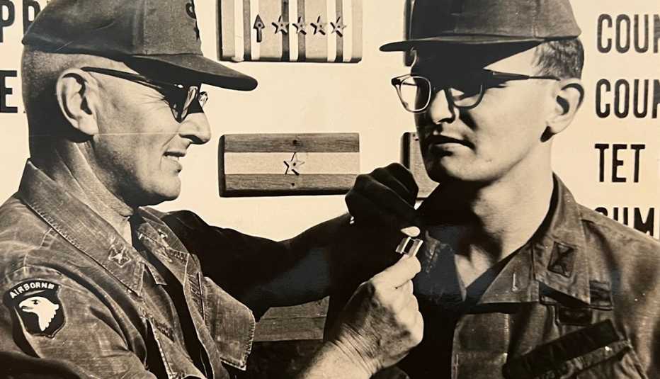 a man is getting something pinned to his uniform