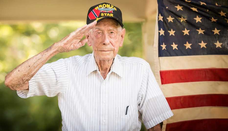 a man in a hat salutes with a flag behind him