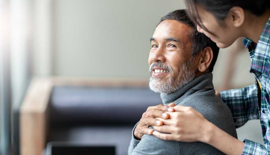 A woman puts her hands on a man's shoulders