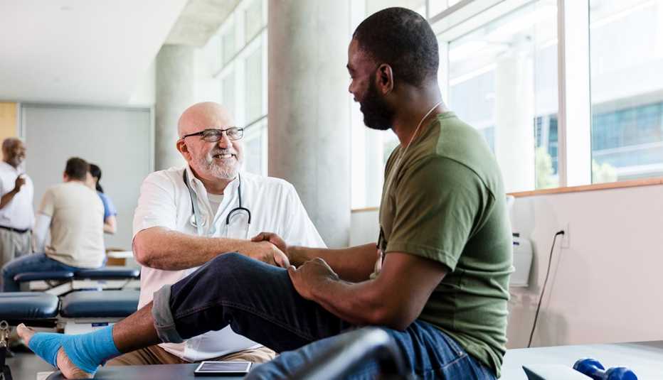 A man sitting on a bed being treated by a doctor A man sitting on a bed being treated by a doctor