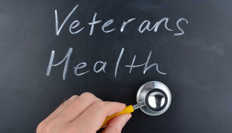 Veterans health handwritten on a blackboard in white chalk with a doctors hand holding a stethoscope.