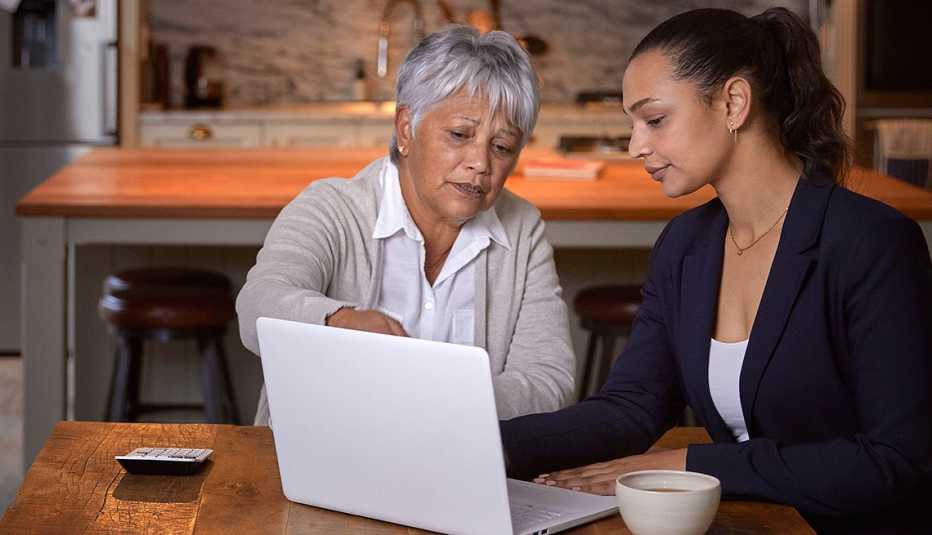 two women sitting at a table looking at a computer