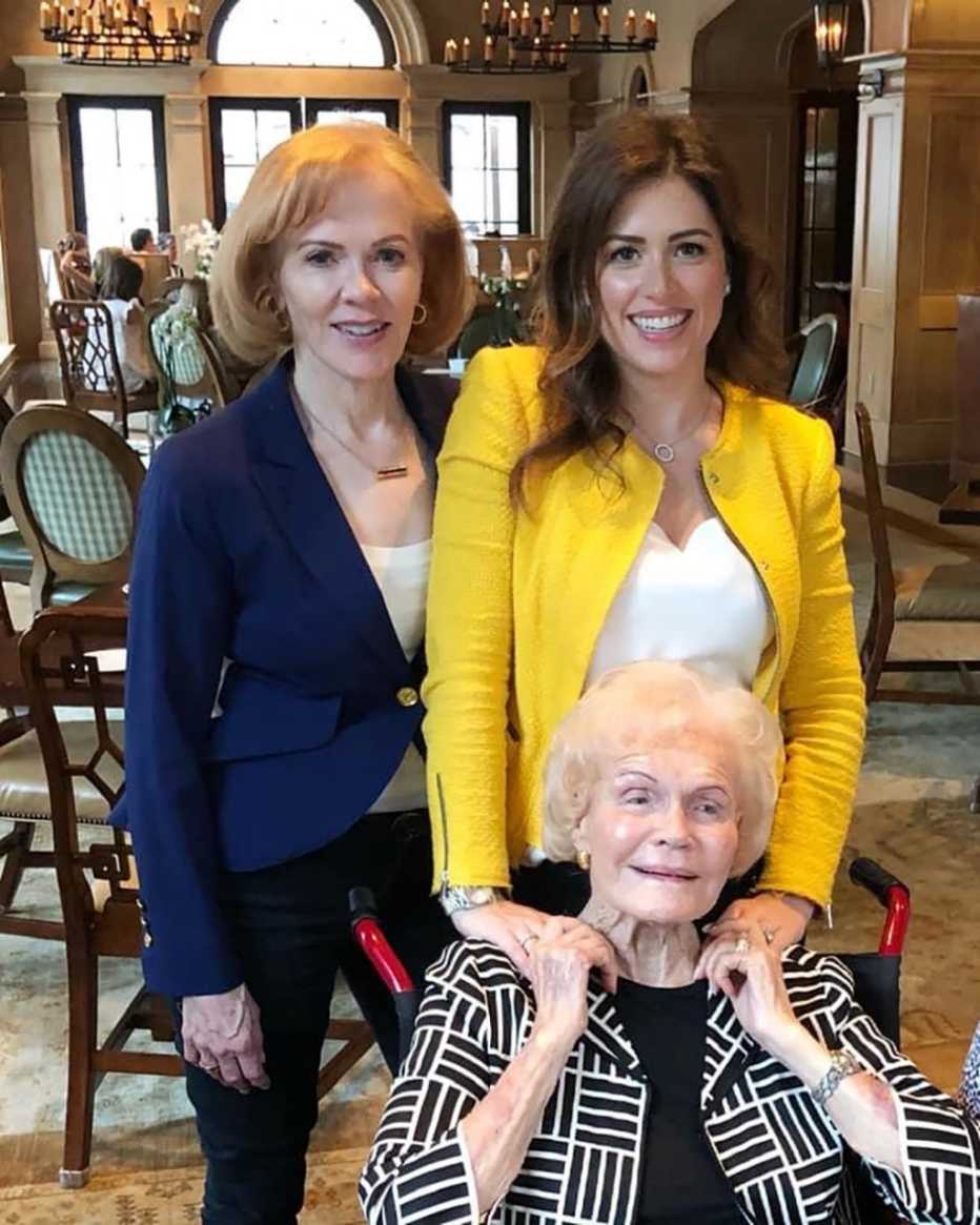two women standing behind one woman who is sitting