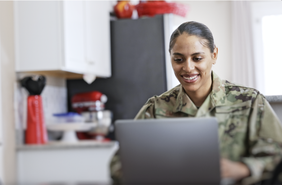 a person in military uniform uses a laptop computer at home